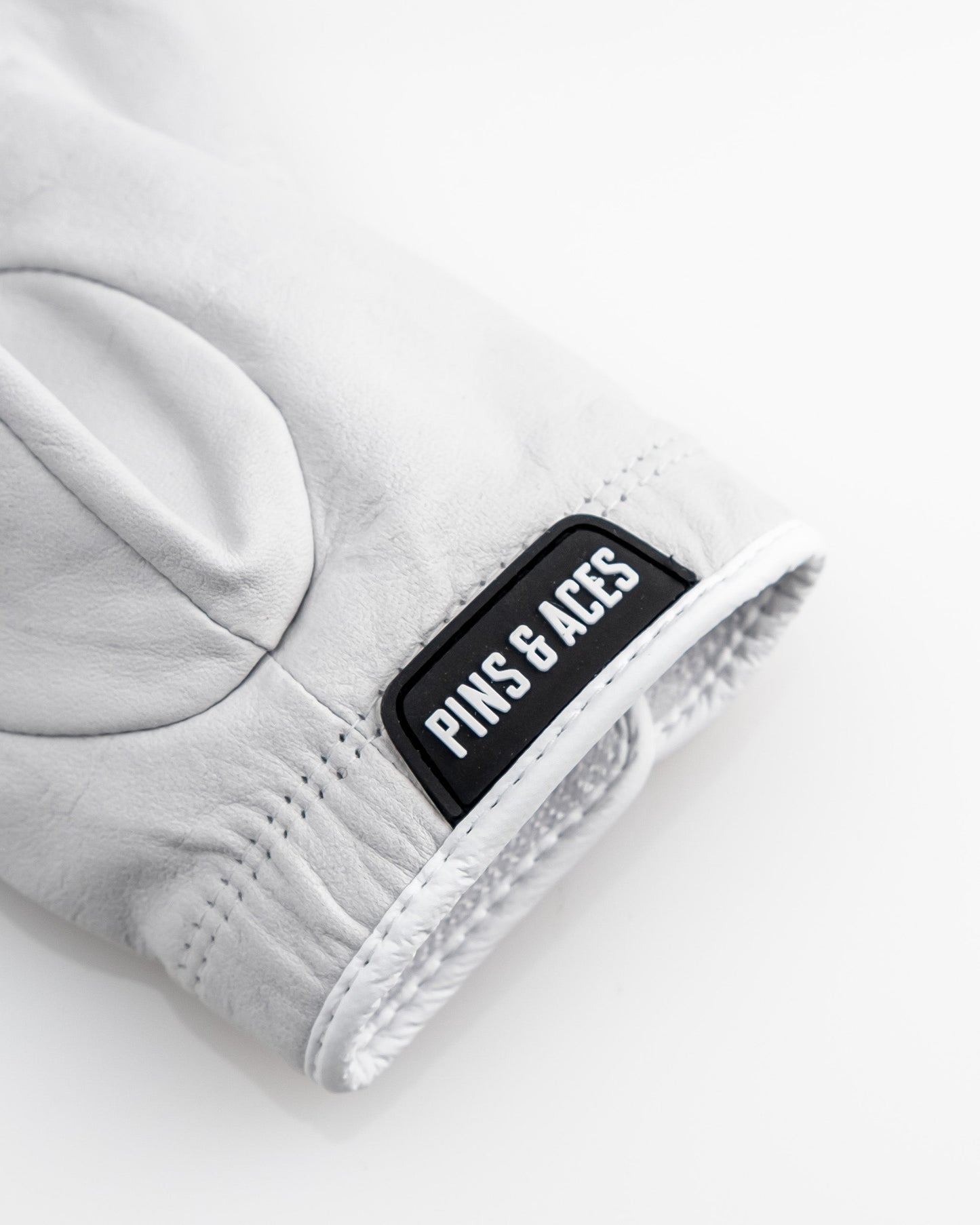 Premium Tour Glove in Ghost White featuring a sleek design and the Pins & Aces logo for stylish performance on the golf course.
