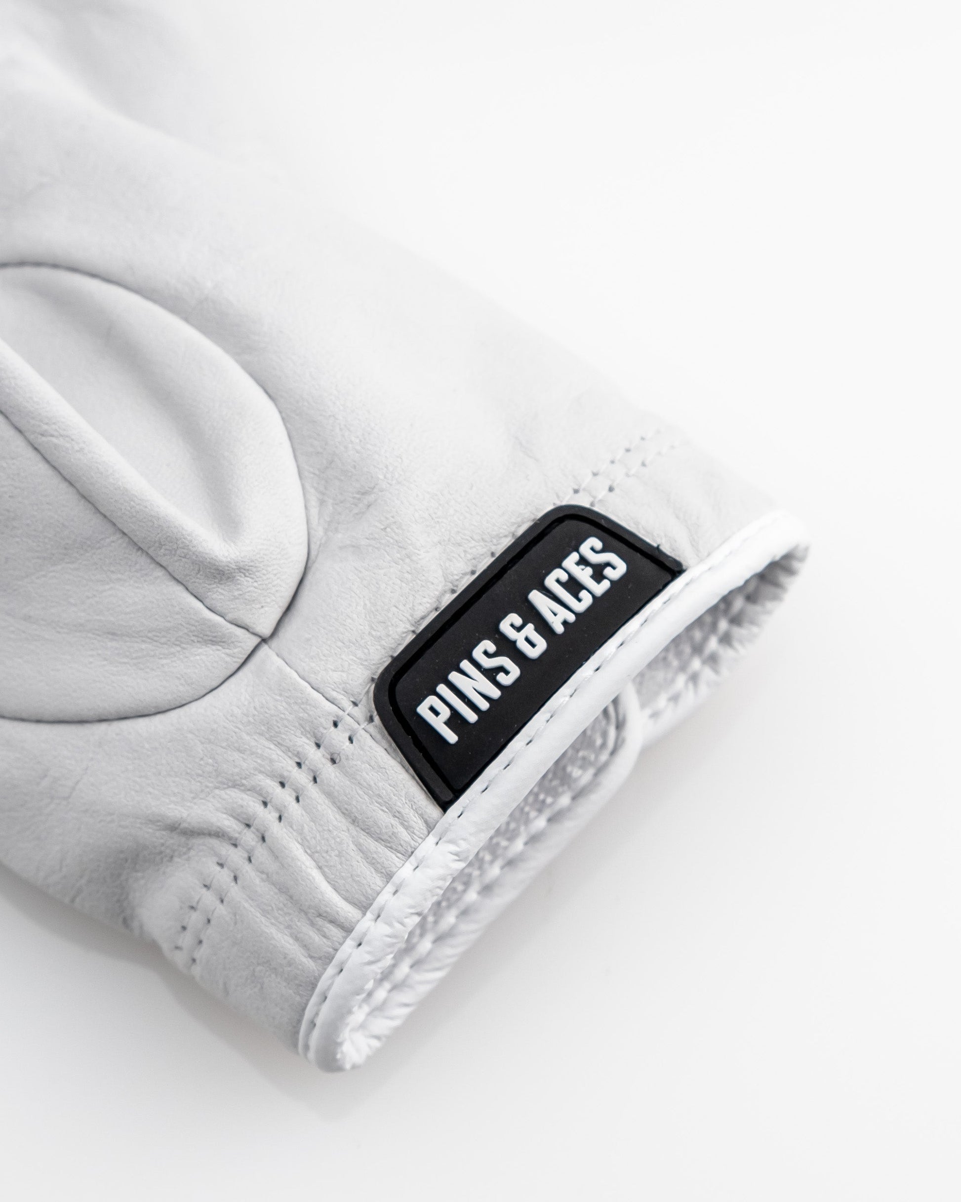 Premium Tour Glove in Ghost White featuring a sleek design and the Pins & Aces logo for stylish performance on the golf course.