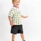 Youth in a TMNT-themed polo shirt featuring colorful 8-bit turtle graphics, paired with black shorts and sneakers.