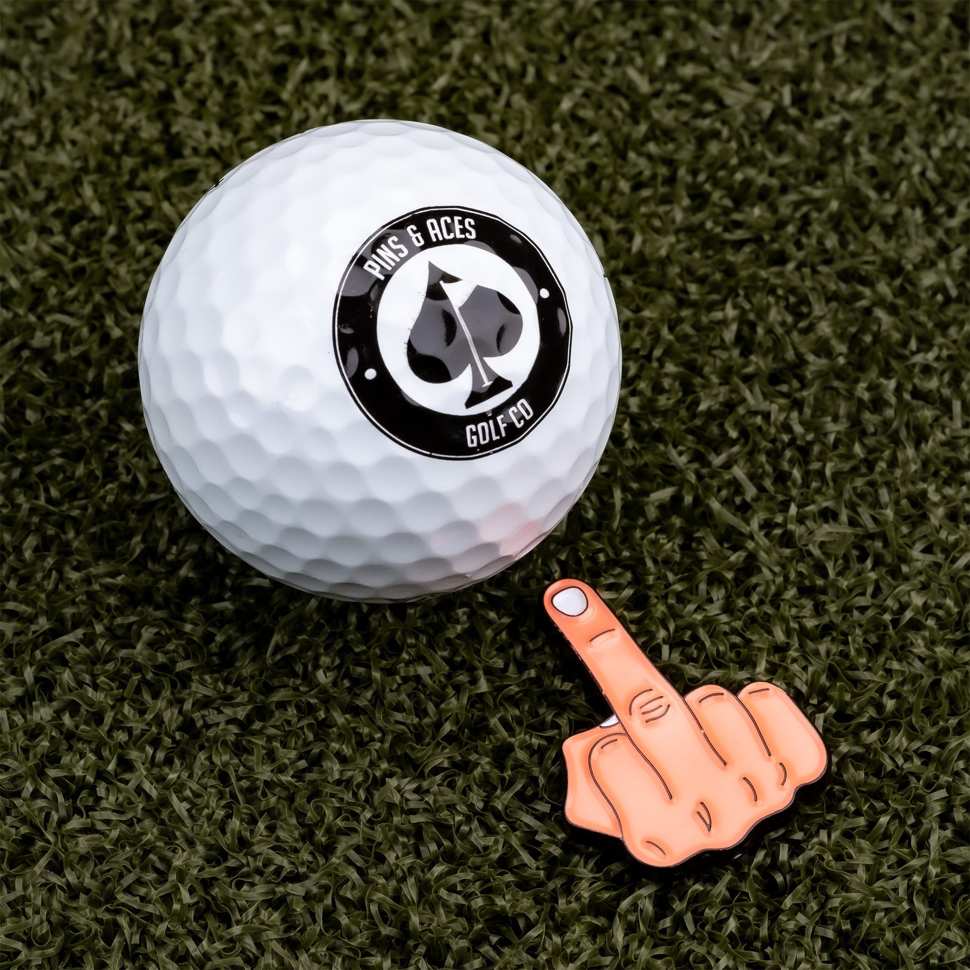 Middle finger ball marker featuring a colorful design, set against a golf ball, on a white background.