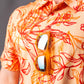 Cabo Sunburst polo shirt in vibrant orange and yellow gradient design, featuring a classic collar and short sleeves.