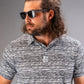 Stylish man wearing a black and white patterned golf polo with sunglasses, showcasing bold golf apparel.