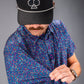 A golfer showcases the Lavender Flower Power polo, featuring a vibrant floral pattern, while adjusting the sleeve.