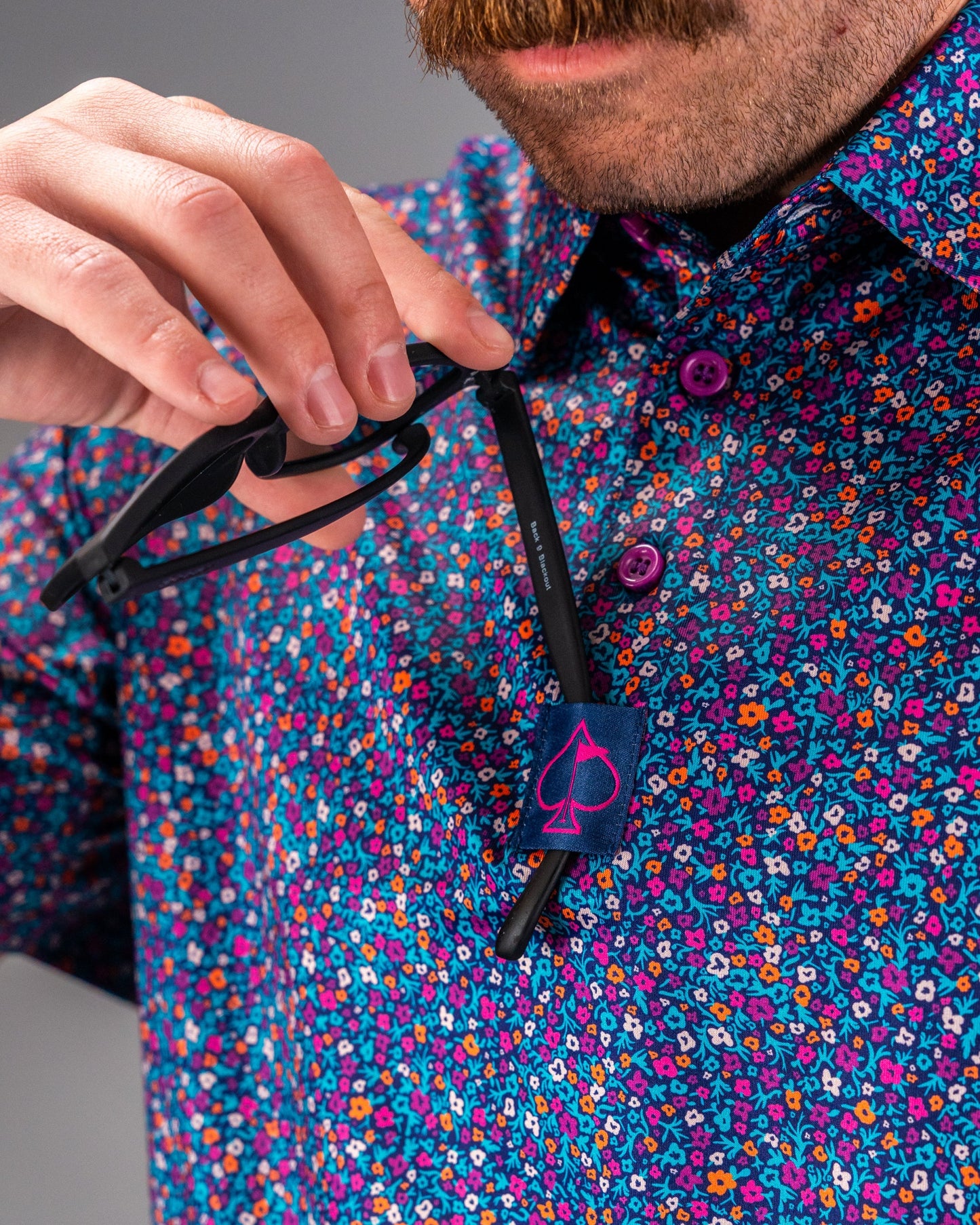 Bold floral golf shirt featuring vibrant lavender and multicolored flowers, with a stylish collar and unique button details.