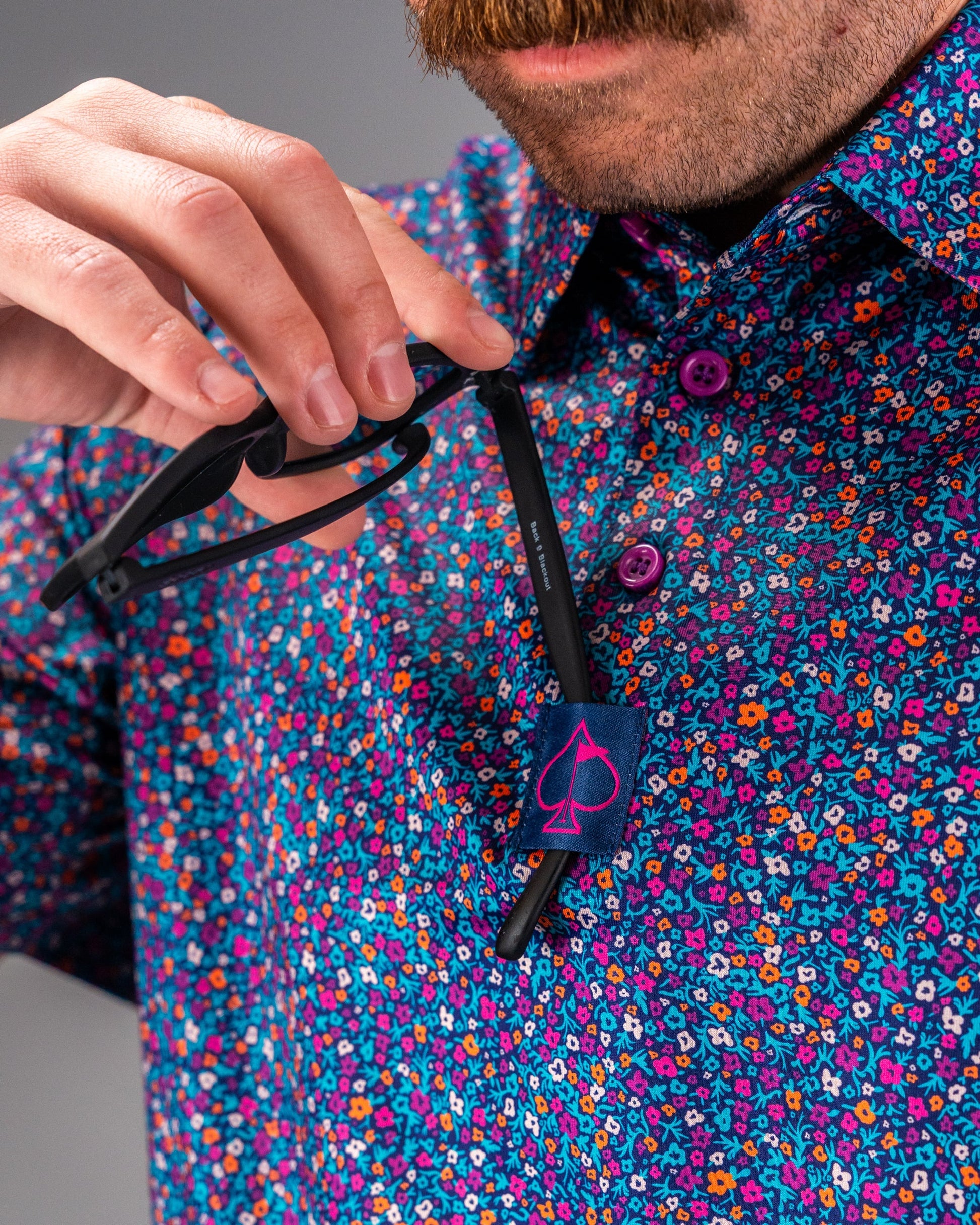 Bold floral golf shirt featuring vibrant lavender and multicolored flowers, with a stylish collar and unique button details.