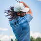 A golfer swings a club, showcasing the Squiggle Blue golf shirt with a textured pattern against a sunny sky.