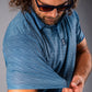 A man in a blue golf polo shirt adjusts the sleeve, showcasing the textured fabric and stylish design.