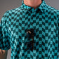 Bold wavy checkered golf polo in teal, featuring a button-up collar and sunglasses draped over the front.