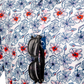 Colorful hibiscus-patterned shirt with sunglasses hanging from the collar, showcasing a vibrant tropical design.