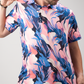 A golfer showcases a vibrant Melting Floral polo shirt featuring a bold pink and blue floral pattern.