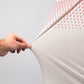 Close-up of a hand stretching the Player Preferred™ Polo - Spade Fade Light fabric, showing its light, flexible, and patterned material.