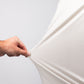 Close-up of a hand stretching a white Player Preferred™ Polo - Vapor Spade fabric, showing its stretchability and texture.