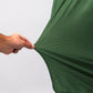 Close-up of a hand pulling the hem of a green Player Preferred™ Polo shirt with Forest Wave pattern, showing textured fabric.