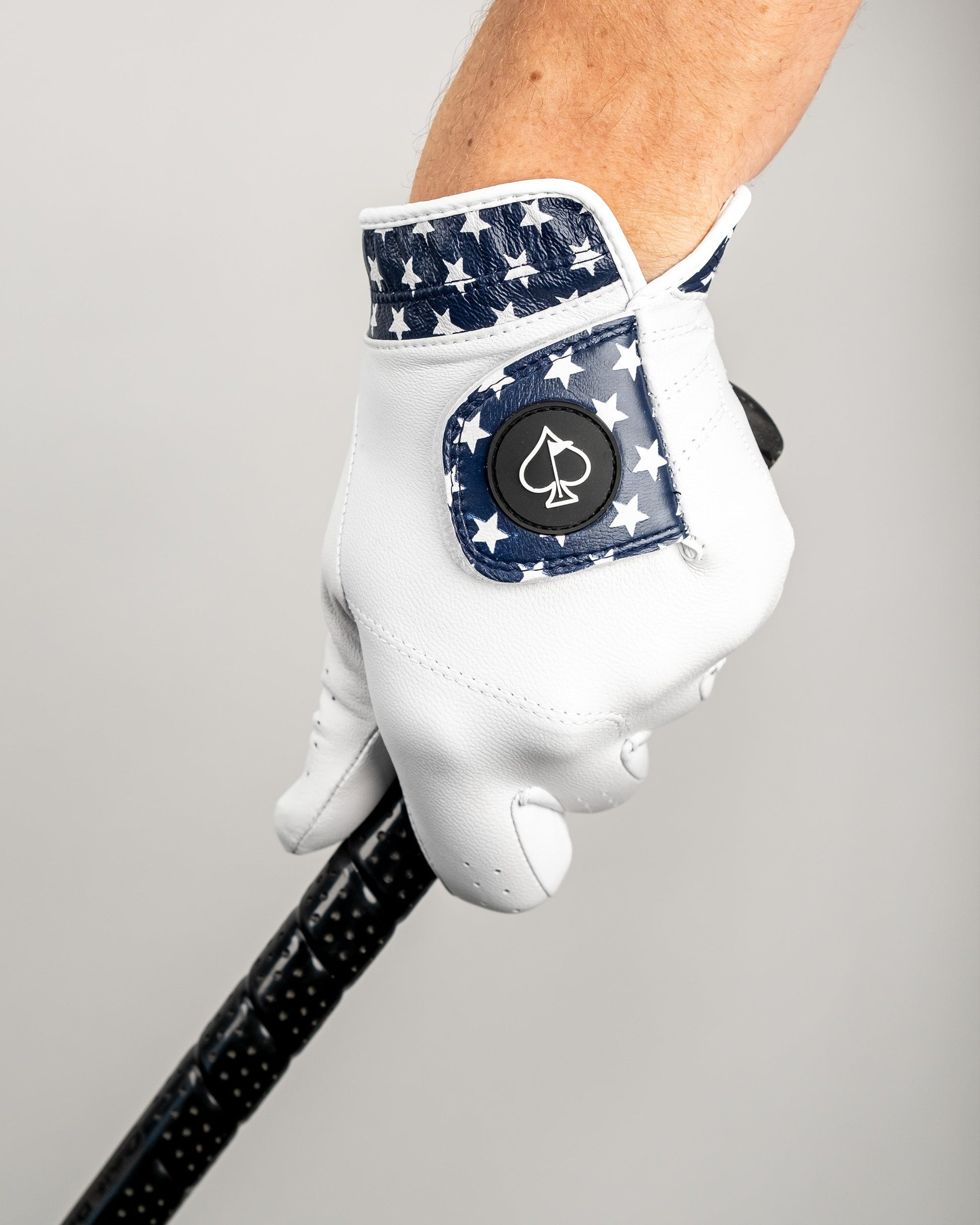 Premium Tour Glove featuring a white base with a navy star pattern and a spade logo, designed for stylish golfers.