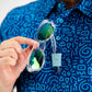 A person holds sunglasses while wearing a blue TMNT-themed shirt featuring a doodle pattern.