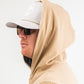 Performance golf hoodie in sand color, featuring a relaxed fit and a hood, paired with a cap and sunglasses.