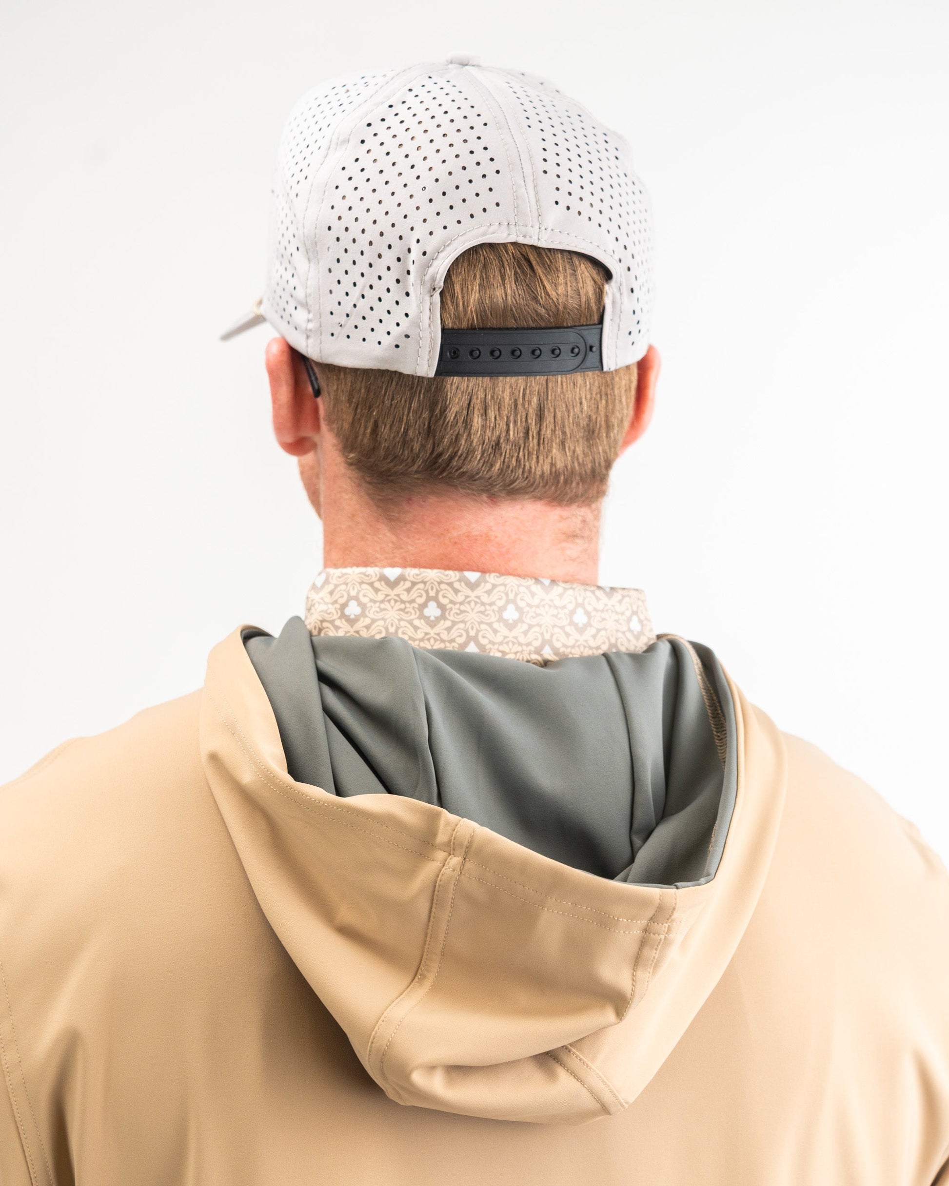 Men's performance golf hoodie in sand color, featuring a lightweight design and stylish layered look with a patterned collar.