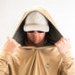 Man wearing a sand-colored performance golf hoodie with the hood up, showcasing a logo and a matching cap.