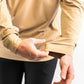 Performance golf hoodie in sand color, featuring adjustable cuffs and a sleek design for comfort on the course.