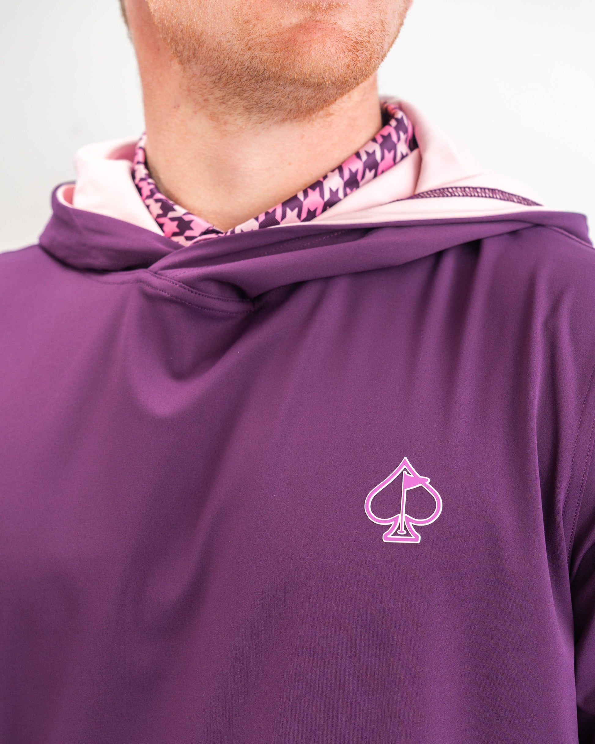 Performance golf hoodie in houndstooth raspberry featuring a stylish design and a logo, ideal for bold golfers.