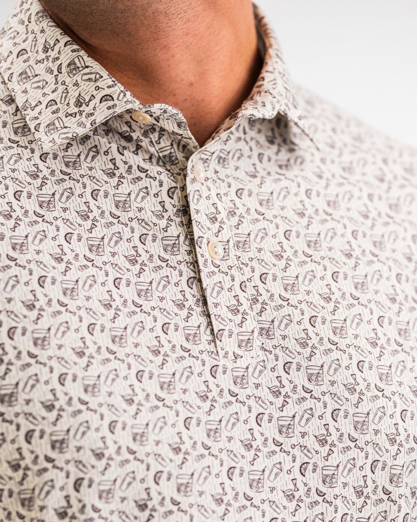 Close-up of the Player Preferred Polo featuring an old-fashioned print with golf-themed designs in neutral tones.
