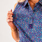 Women's Lavender Flower Power golf shirt featuring a vibrant floral pattern and a stylish logo on the collar.