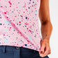 Women's pink splatter golf top featuring a vibrant design with colorful splashes, paired with navy golf pants.