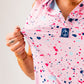Women's pink splatter golf polo featuring colorful paint splashes, designed for a bold and stylish look on the course.