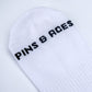 White crew socks featuring "Pins" lettering in black on the side.