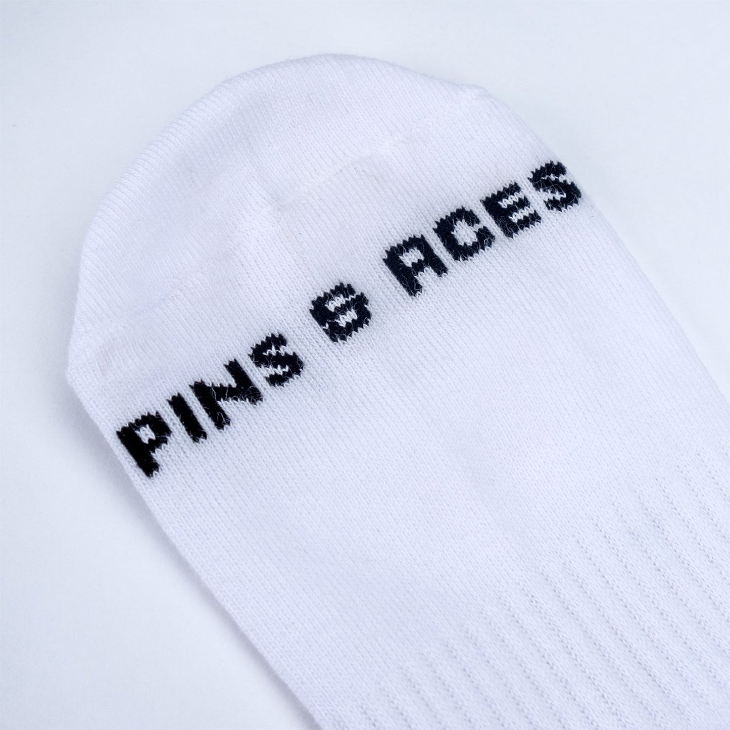 White crew socks featuring "Pins" lettering in black on the side.