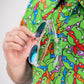 "TMNT Mean Green polo shirt featuring colorful turtle head designs on a vibrant green background."