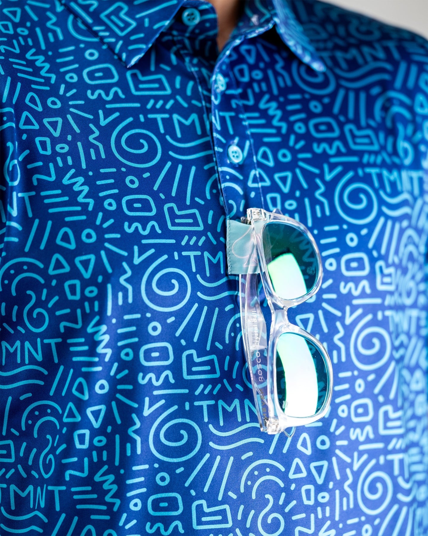 TMNT Doodle polo shirt featuring cartoon-style illustrations of Teenage Mutant Ninja Turtles and colorful accents.