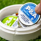 "6 Milly Cool Mint ball marker in a round container, showcasing vibrant packaging on green grass.