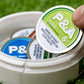 Hand holding a 6 Milly Citrus ball marker from a container with various colored markers on green turf.